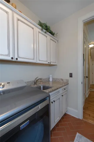 An efficient utility space features timeless custom cabinetry, stone counters, and durable tile flooring.