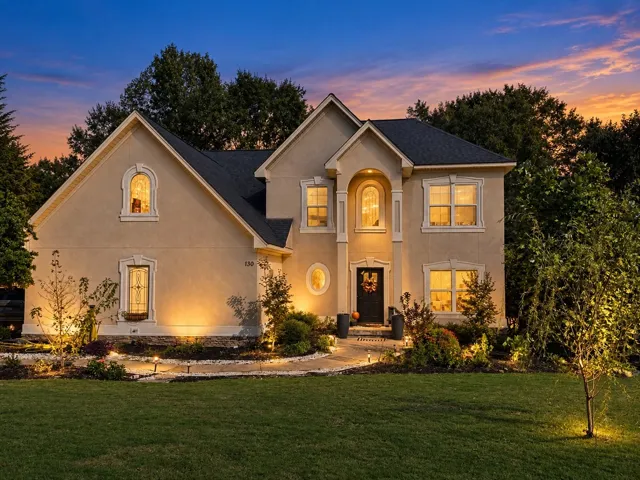 A classic stucco exterior is illuminated against a twilight sky with meticulous landscape lighting.