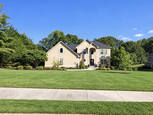 A classic stucco exterior sits framed by manicured green lawns and mature trees.