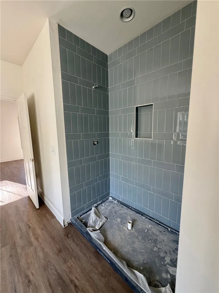 Custom vertical tile detailing highlights this walk-in shower during its final stages of completion.