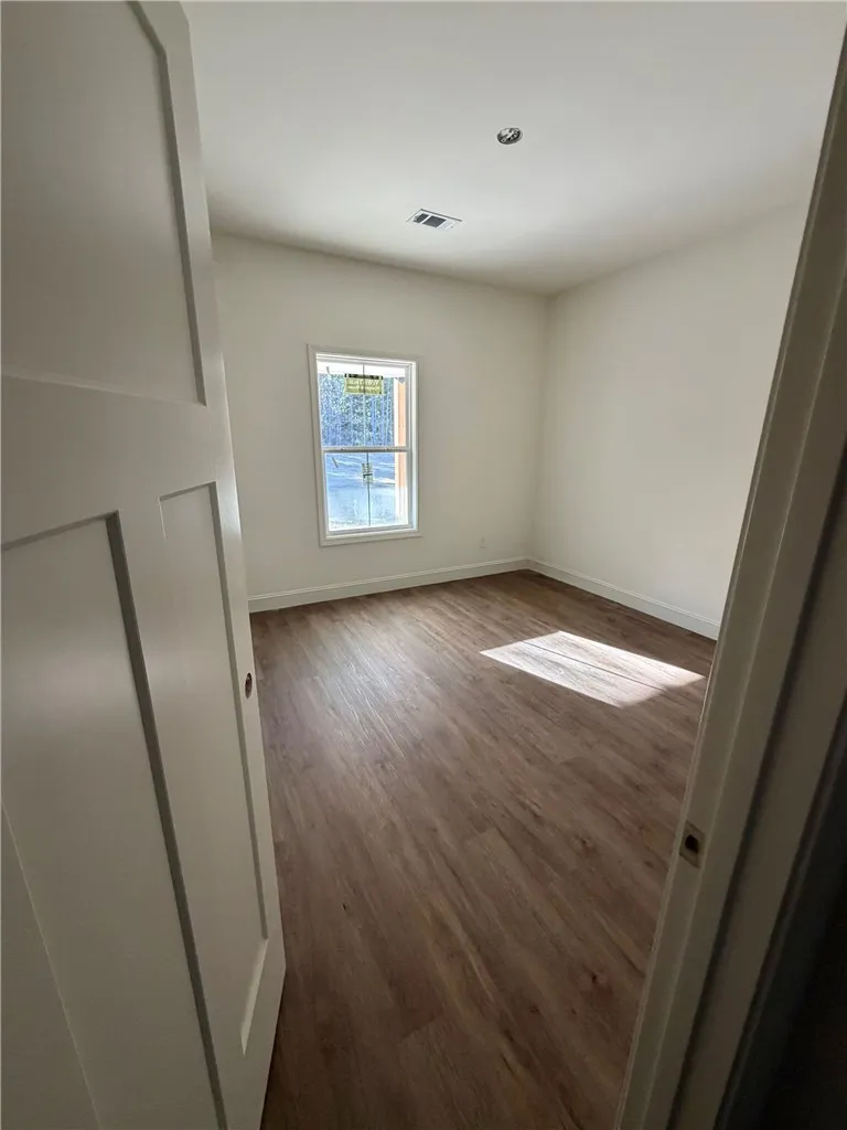 Warm wood flooring and natural light define this clean, versatile bedroom space.