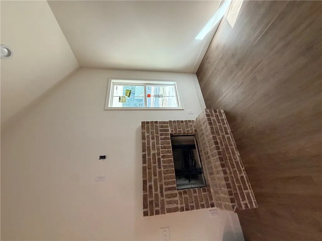 An inviting brick fireplace accents this comfortable living space with warm wood-look flooring.