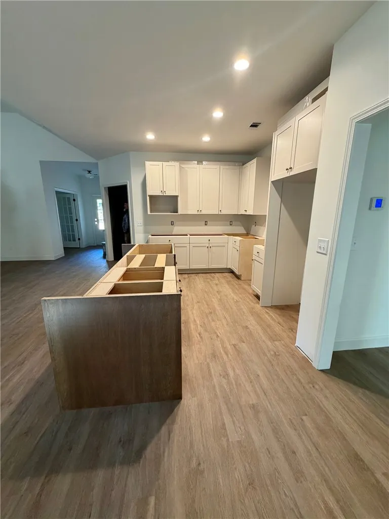 Gleaming recessed lighting illuminates the classic shaker cabinetry and textured wood-look flooring.