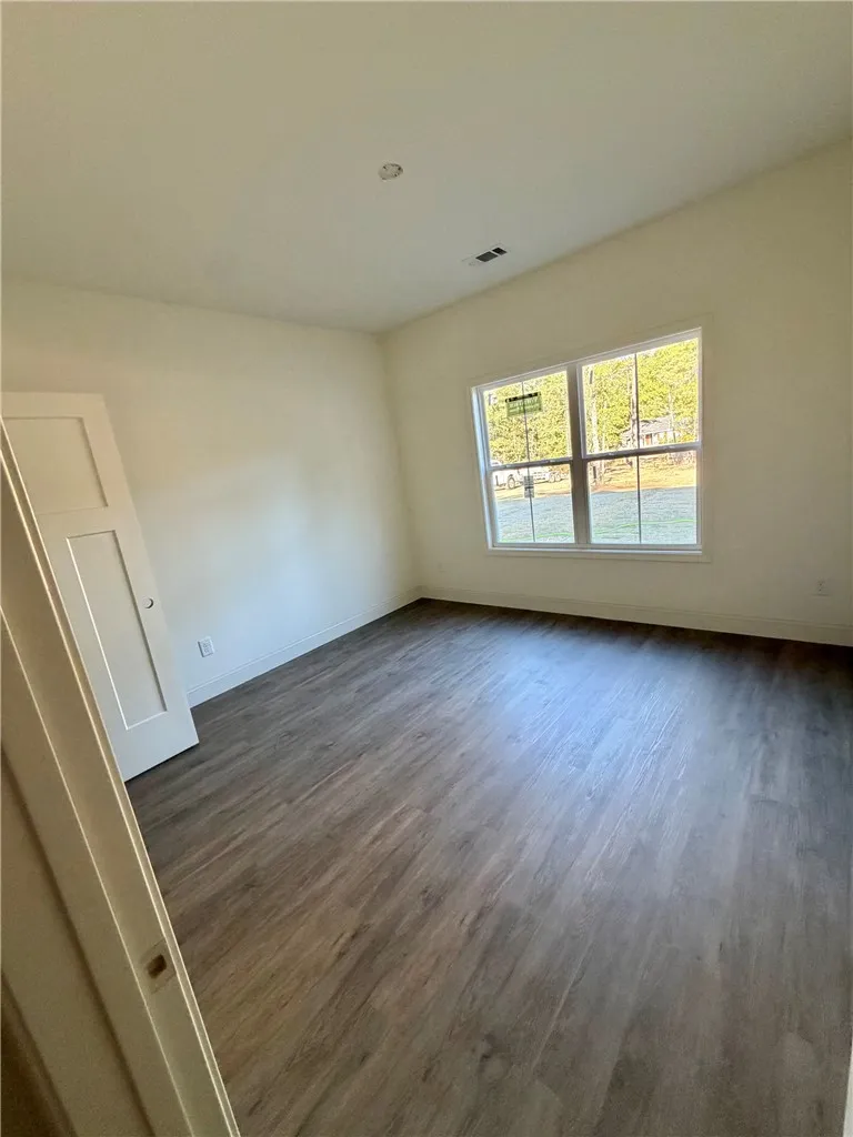 Rich wood-look flooring and a large multi-pane window elevate this versatile, clean-lined bedroom.