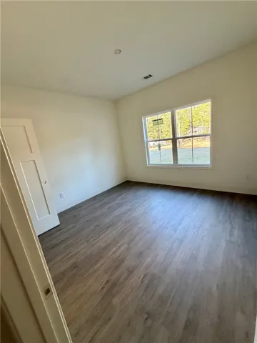 Rich wood-look flooring and a large multi-pane window elevate this versatile, clean-lined bedroom.