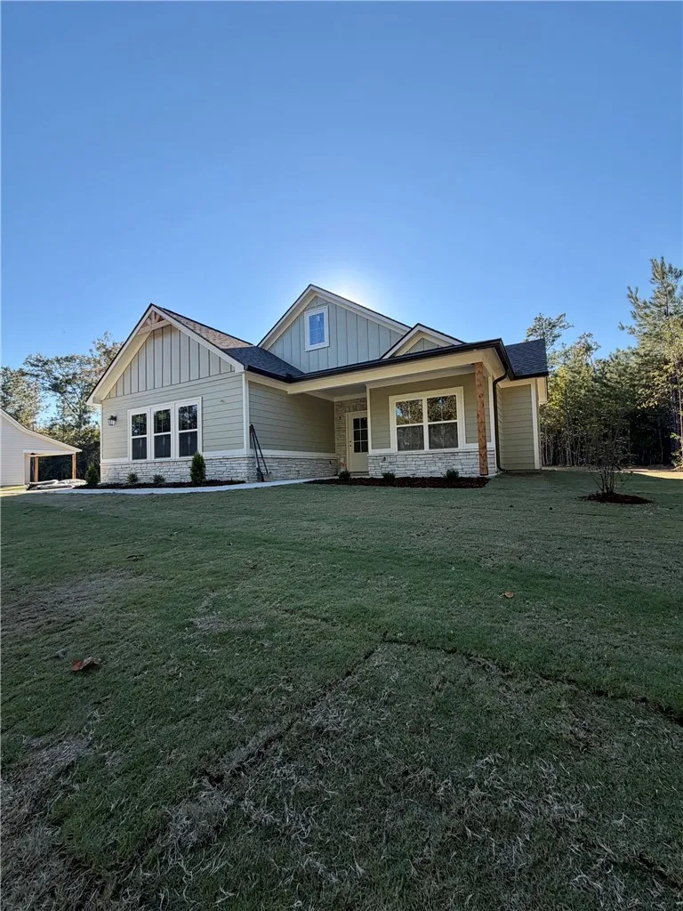 A classic craftsman facade combines stone accents and board-and-batten siding under a clear blue sky.