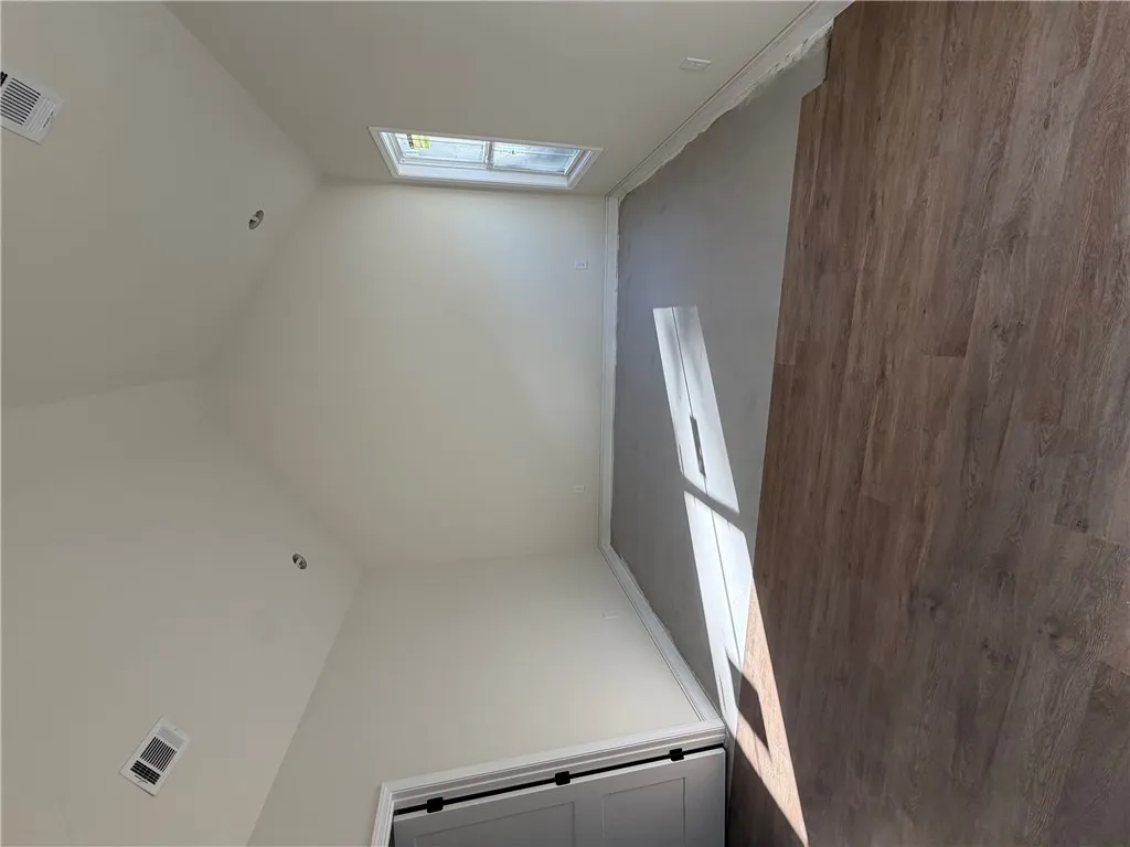 A high, vaulted ceiling and wood-look flooring enhance this light-filled bonus room.