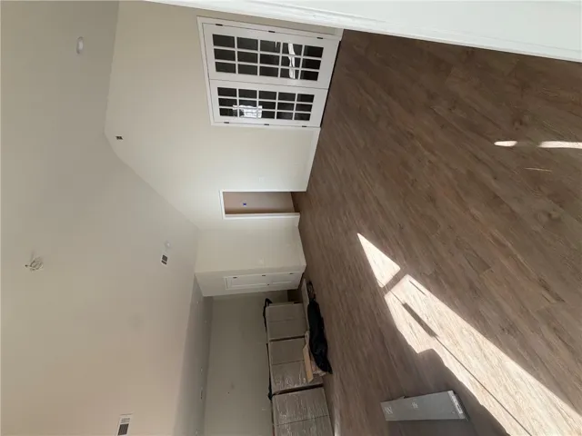 Angled wood flooring runs alongside a towering vaulted ceiling highlighted by recessed lighting.