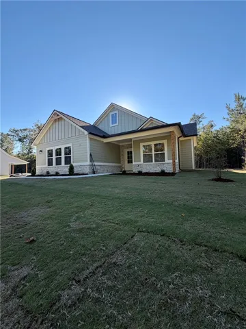 A classic craftsman facade combines stone accents and board-and-batten siding under a clear blue sky.