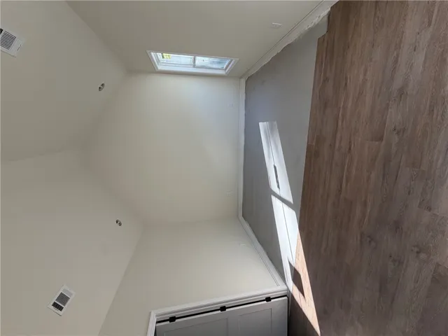 A high, vaulted ceiling and wood-look flooring enhance this light-filled bonus room.