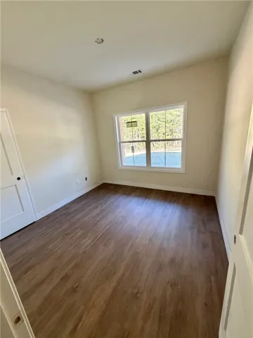 Rich wood floors and a large multi-pane window anchor this comfortable, neutral-toned bedroom space.