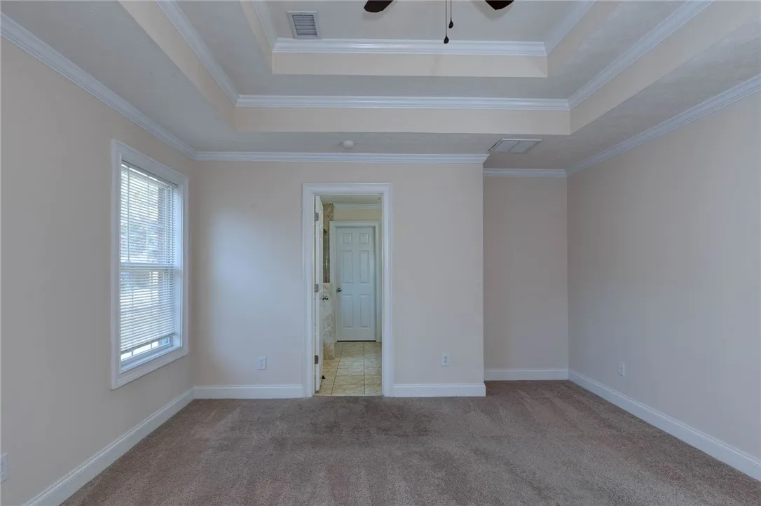 Plush carpeting and elegant tray ceilings enhance this spacious bedroom suite.