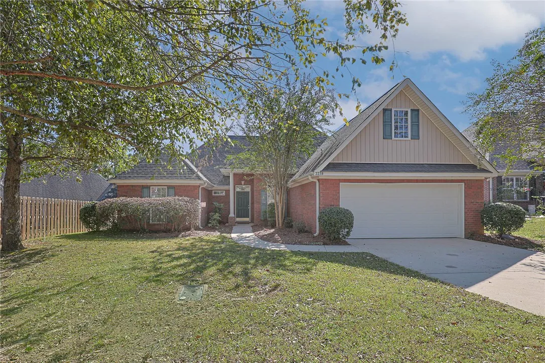 A classic brick exterior and attached garage anchor this charming home under mature shade trees.