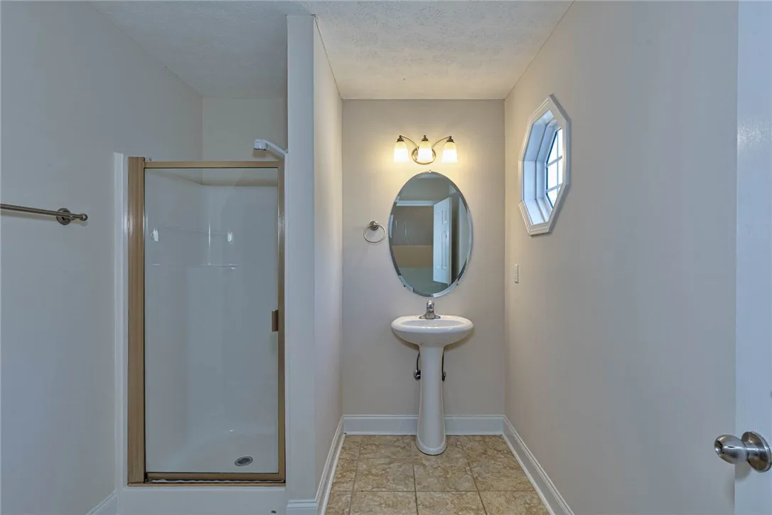 An elegant pedestal sink and tile flooring define this classic secondary bathroom layout.