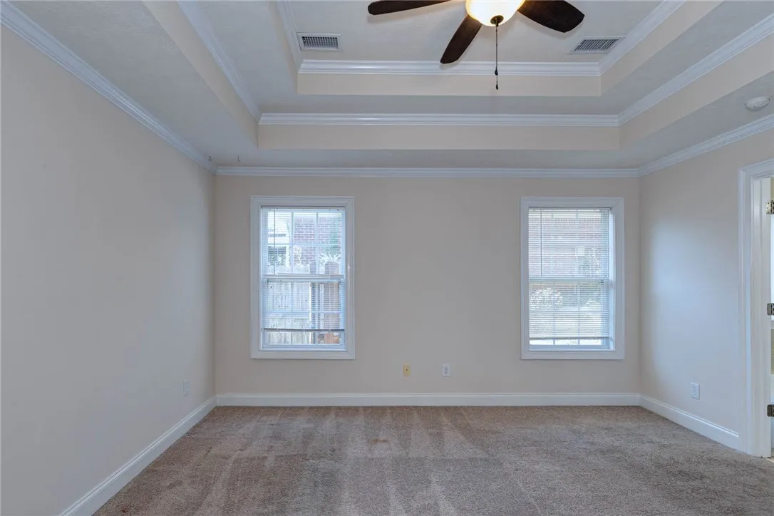 Plush carpeting anchors this elegant space detailed with a tray ceiling and crisp crown molding.