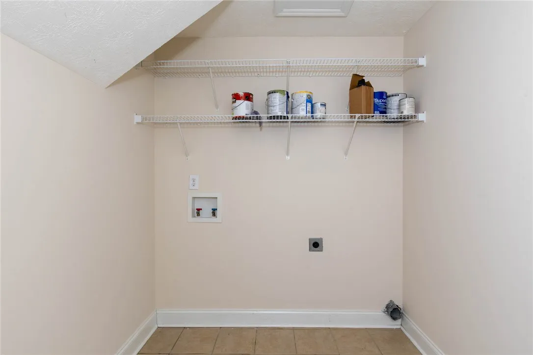 Functional utility space features durable tile flooring and convenient built-in wire shelving.