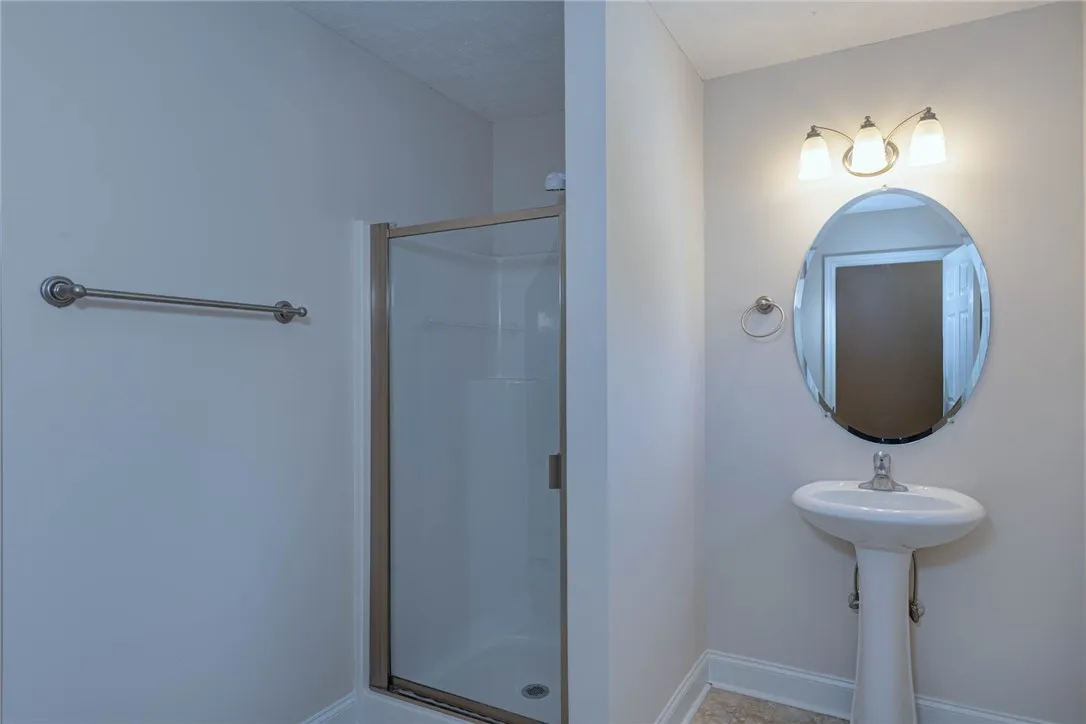 A classic pedestal sink pairs with a glass-enclosed walk-in shower in this functional bathroom.