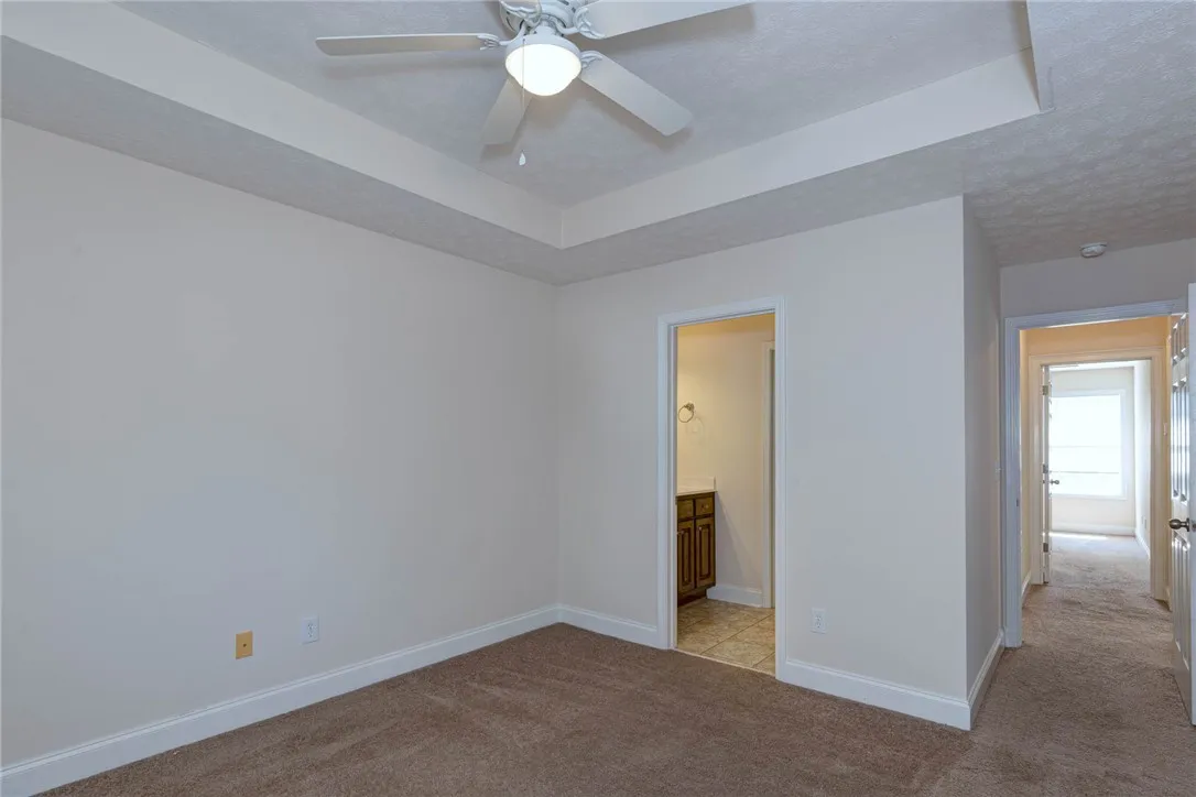 An elegant tray ceiling accents this versatile space featuring plush carpeting and an adjoining bath.