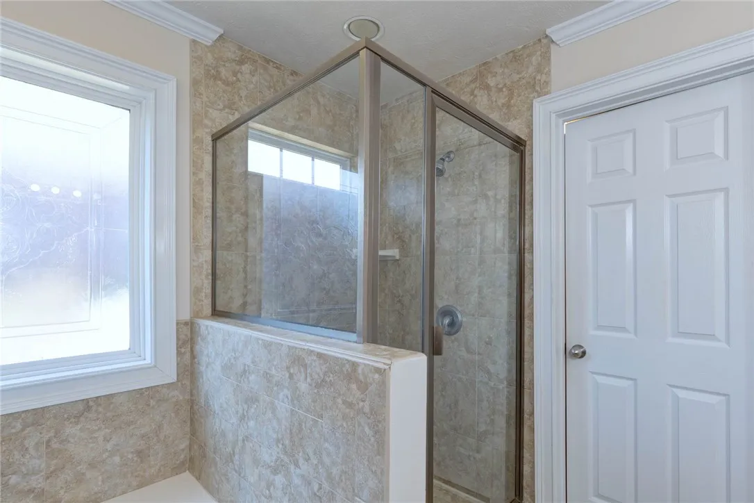 A glass-enclosed walk-in shower features classic tile surrounds and crisp white trim details.