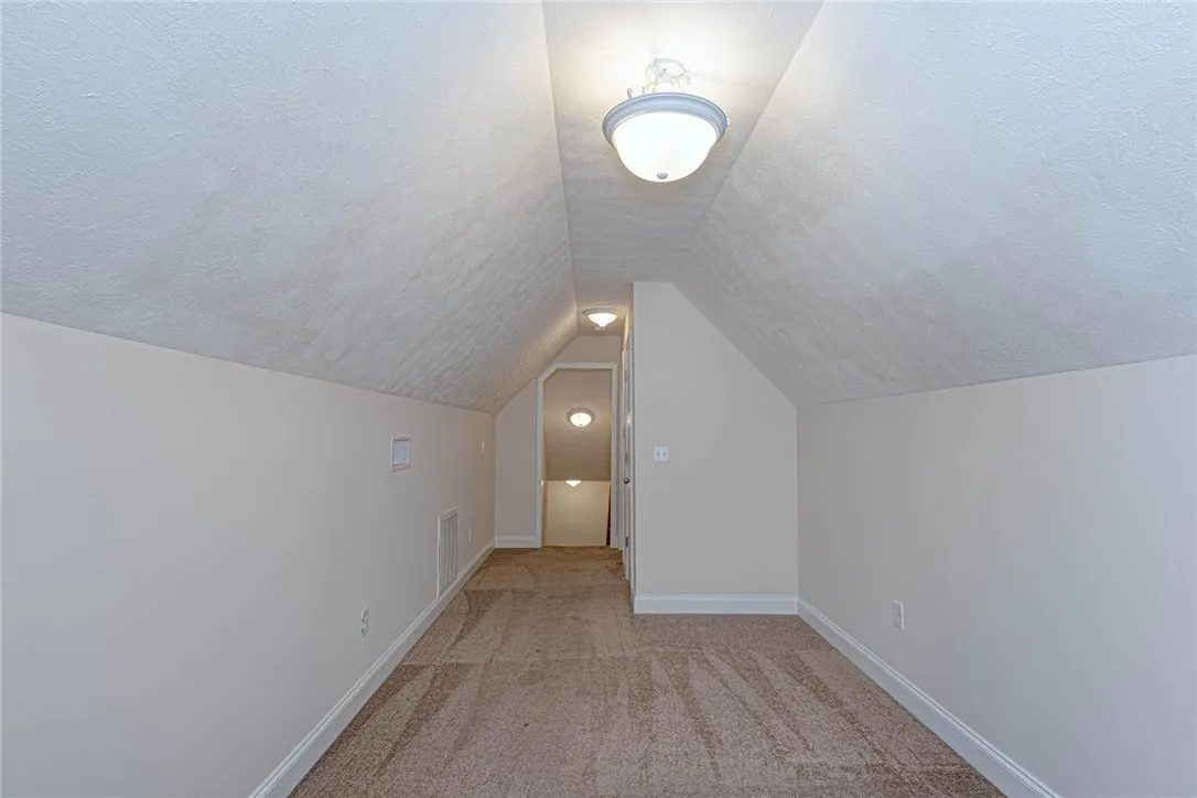 A versatile bonus space highlights vaulted ceilings and neutral carpeting.