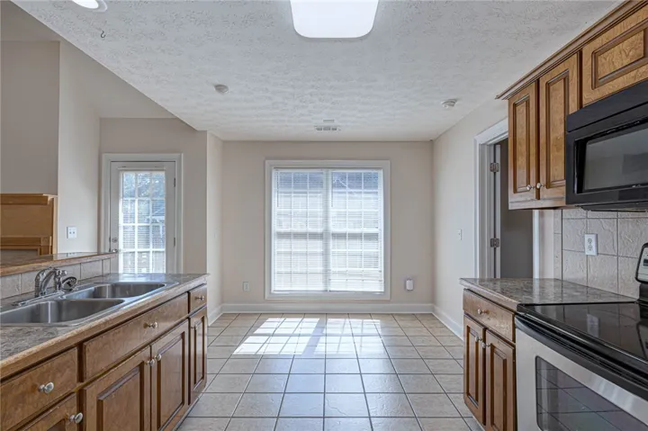 Sunlight streams across the classic tile flooring of this functional eat-in kitchen area.