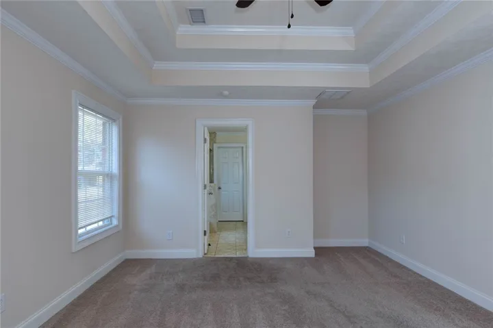 Plush carpeting and elegant tray ceilings enhance this spacious bedroom suite.