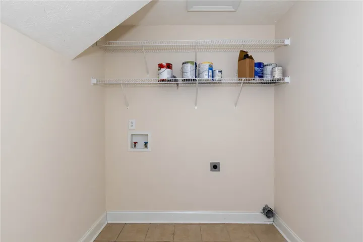 Functional utility space features durable tile flooring and convenient built-in wire shelving.