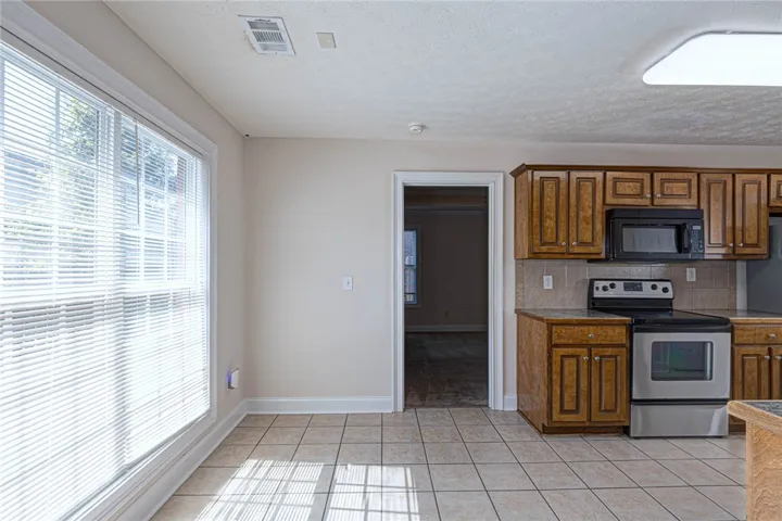 Ample windows invite natural light across the tiled dining area adjacent to the kitchen.