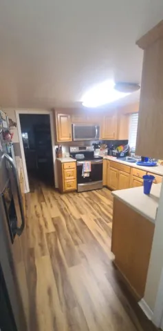 Rich wood-toned flooring anchors this kitchen featuring built-in cabinetry and stainless steel appliances.