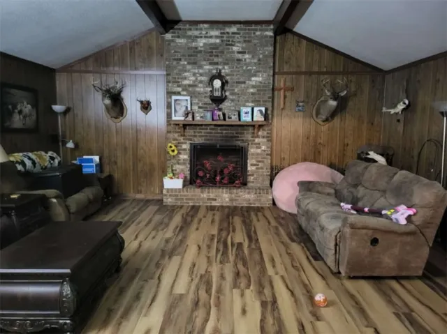 A floor-to-ceiling brick fireplace anchors this rustic room beneath a vaulted, wood-beamed ceiling.