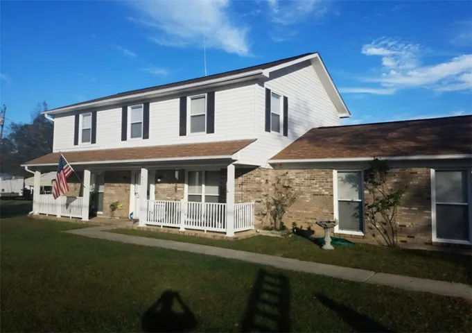 Classic brick and siding exterior features a wide covered front porch and neat concrete walkway.