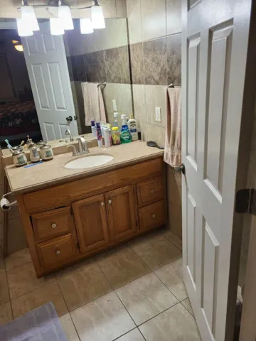 Tiled walls and floors frame a traditional wood vanity in this functional bathroom space.