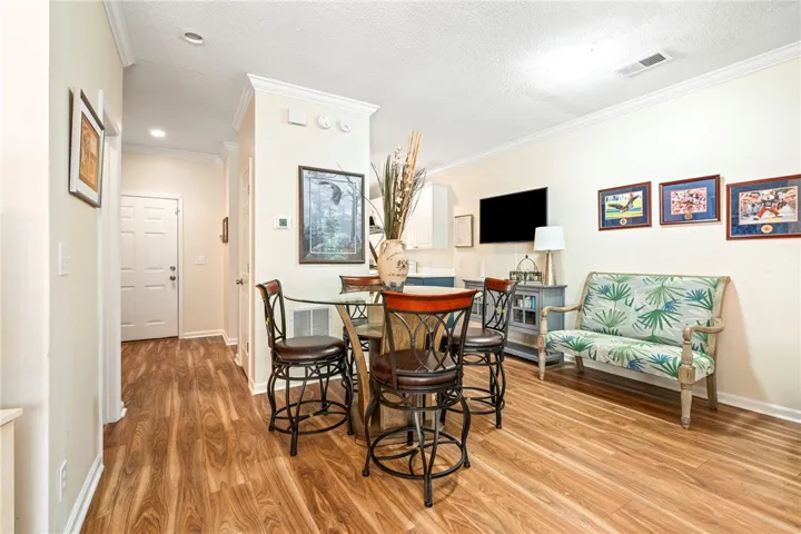 Rich wood-look flooring and crown molding frame this versatile casual dining space.