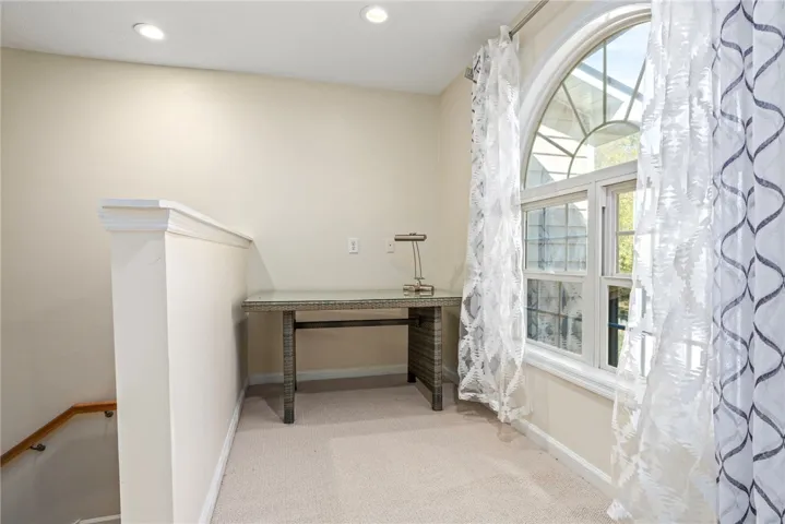 An upper landing features a prominent arched window and recessed lighting.