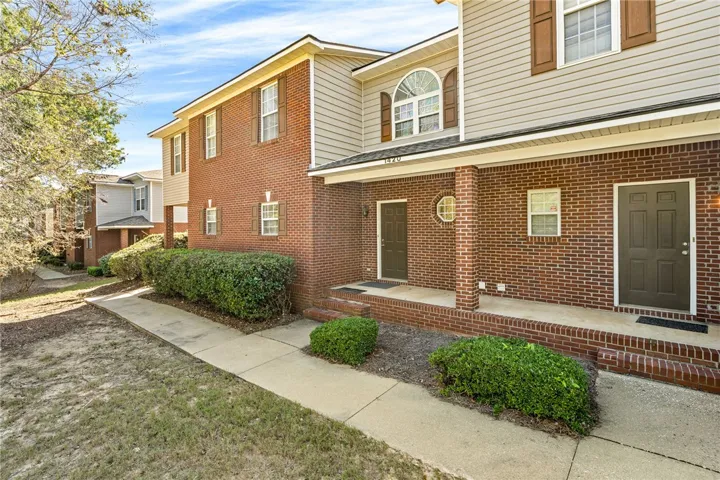 Classic brick and siding accents frame the inviting covered entryway of this multi-level townhome.