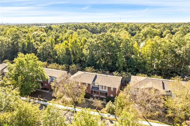 Mature trees frame these multi-level brick townhomes adjacent to a lush wooded backdrop.
