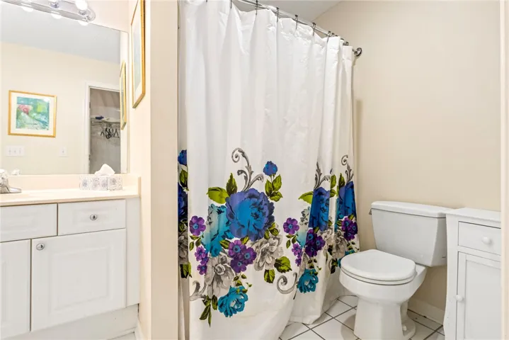 Functional bathroom layout features a white vanity, tiled floors, and a tub-shower combination.