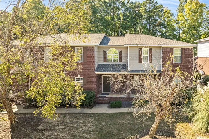 A classic brick facade is accented by vinyl siding details and a multi-gabled roofline.