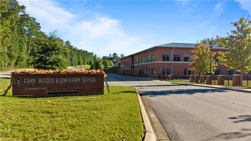 An inviting school entryway is surrounded by mature trees, manicured lawns, and brick architecture.