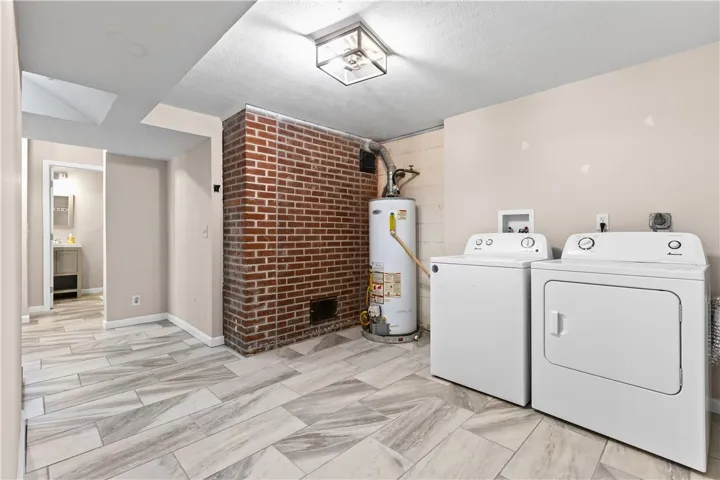 Functional basement laundry space features durable tile flooring and an exposed brick accent wall.