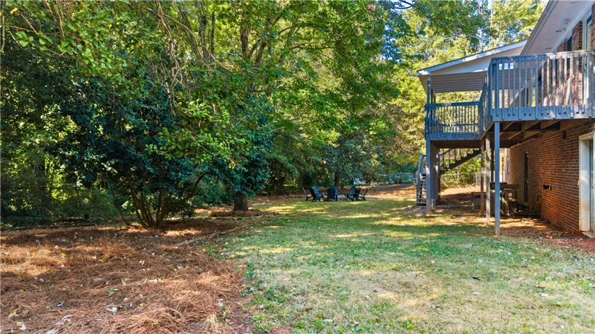 Mature trees frame a grassy lawn bordered by an elevated wooden deck structure.