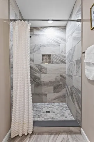 Floor-to-ceiling tiles and a recessed shelf create a streamlined and modern walk-in shower.