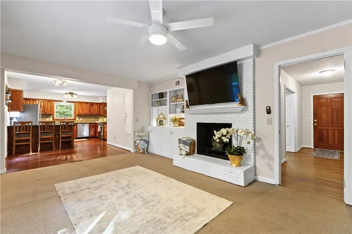 An inviting open floorplan connects the cozy fireplace hearth to the adjacent kitchen area.