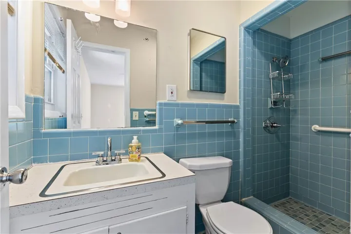 A well-preserved bathroom features classic blue tiling and a matching tiled walk-in shower.