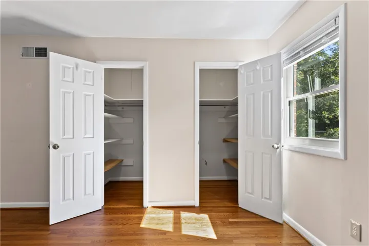 Warm hardwood floors complement dual built-in closets and a sunlit window.