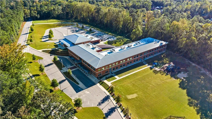 An aerial perspective of Cary Woods Elementary showcases a substantial brick facility surrounded by expansive lawns and mature woodlands.