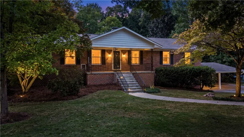 An inviting brick elevation framed by mature trees features a welcoming front porch and walkway.