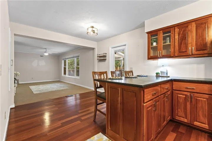Rich wood flooring connects the functional kitchen area seamlessly to the adjacent living space.