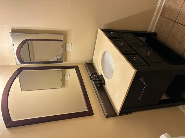 A single vanity features stone counters and dark wood cabinetry alongside tile flooring.