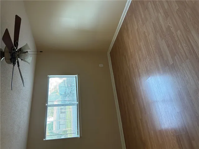 A spacious room features classic wood-style flooring and a large window providing ample natural light.